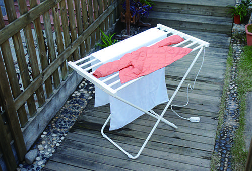 Séchage d'une veste pour enfants sur un séchoir à plancher sur une terrasse