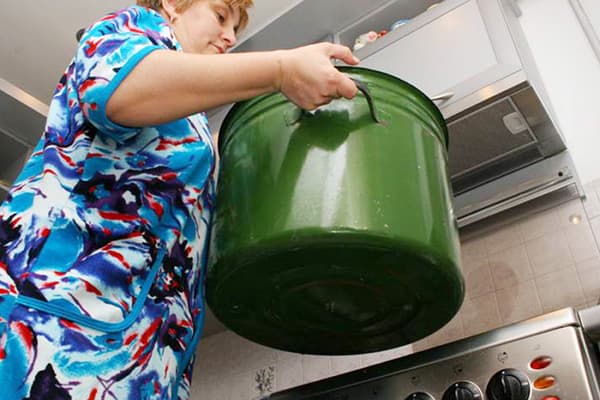 Woman holds pot for boiling laundry
