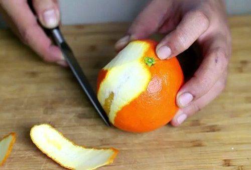 skreller en appelsin med en kniv