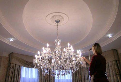woman cleans a crystal chandelier