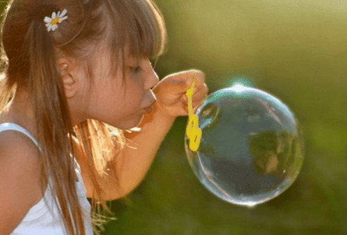 little girl blows up a soap bubble