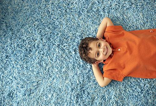 A fiú fekszik egy tiszta szőnyegen