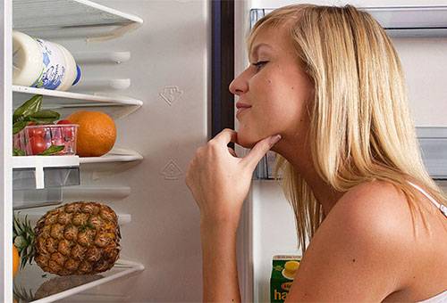 Menina estabelece frutas e legumes na geladeira