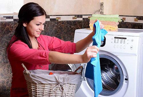 Woman pulls out the laundry from the washing machine