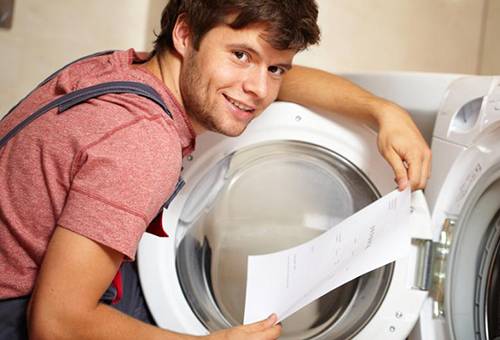 Một người đàn ông đang nghiên cứu các hướng dẫn cho máy giặt