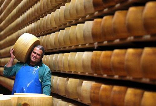Um homem em um armazém carrega uma cabeça de queijo