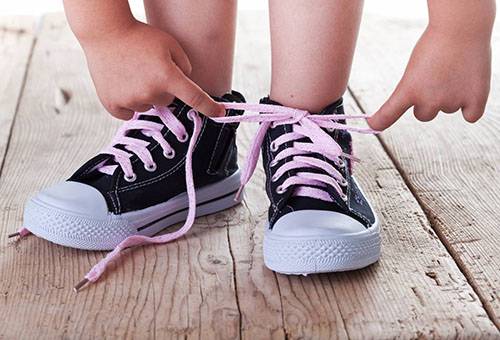 Child tying shoelaces on sneakers