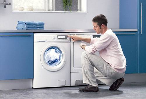 Sinusuri ng isang lalaki ang operasyon ng isang washing machine