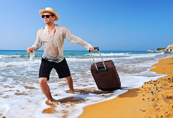 Ember a tengerparton egy bőrönddel