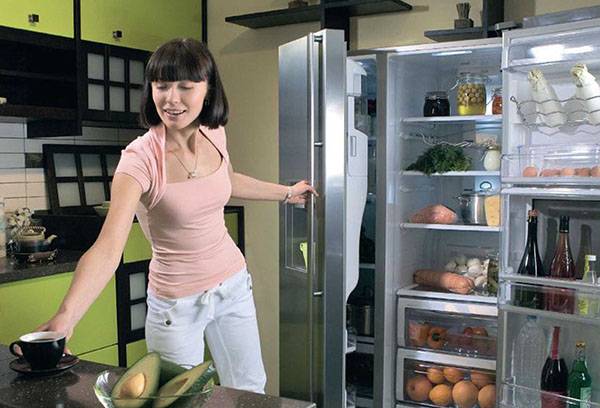 Femme prend des aliments dans le réfrigérateur