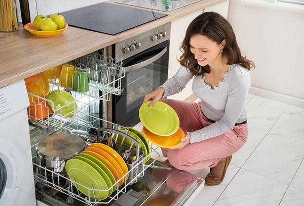 The girl unloads the dishwasher