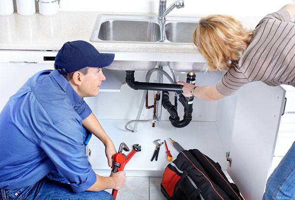Woman shows plumbing to flow under the sink