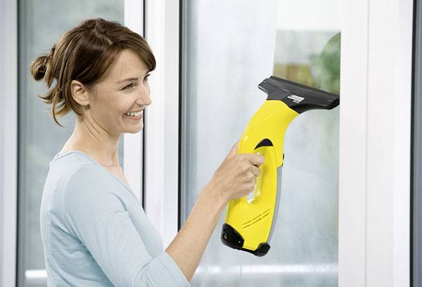 Girl cleans windows with Karcher wiper
