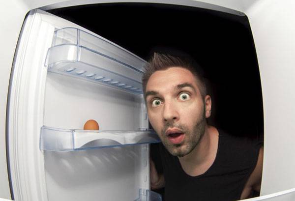 Een man kijkt in de koelkast