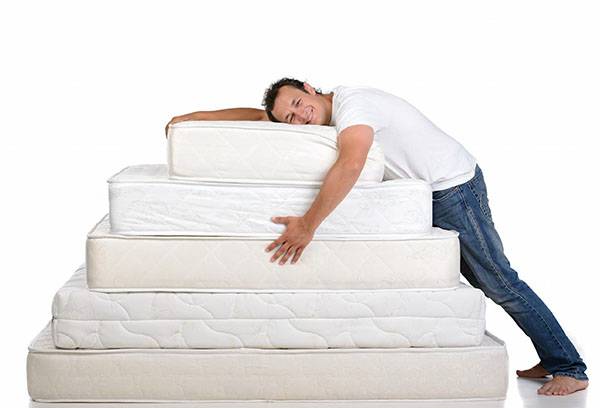 A man with a mountain of mattresses