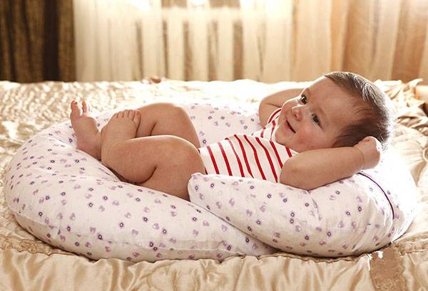 Baby lies on a pillow for feeding