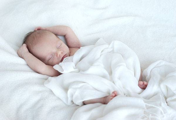 Slapende baby onder een lichte deken