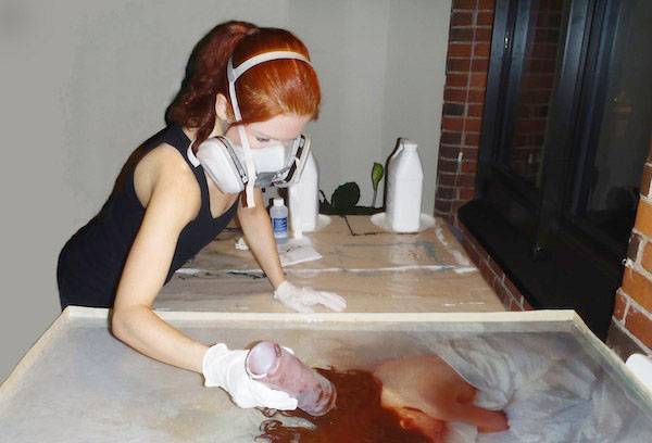A girl in a respirator works with epoxy