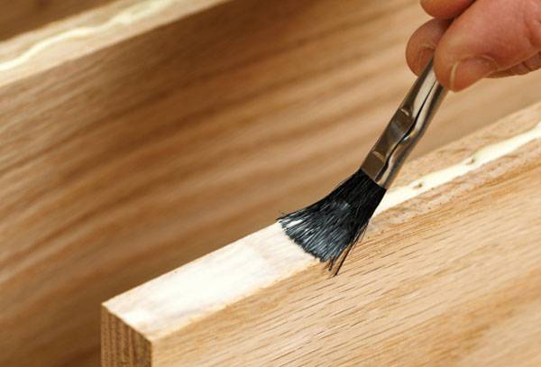 Putting glue on a wooden element of furniture