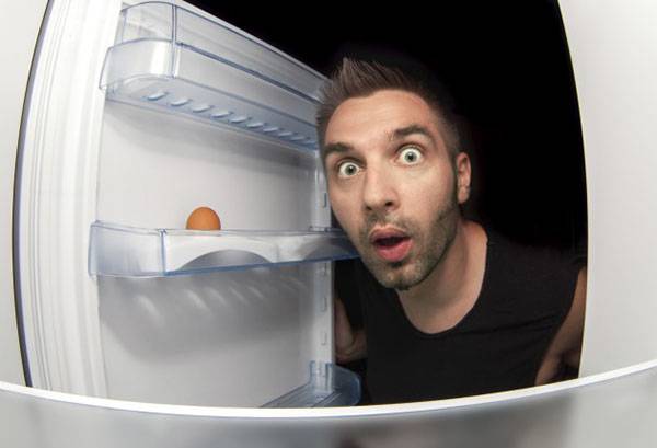 Um homem olha na geladeira