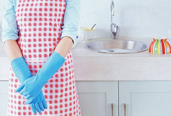 ผู้หญิงในผ้ากันเปื้อนและถุงมือที่ใช้ในครัวเรือน