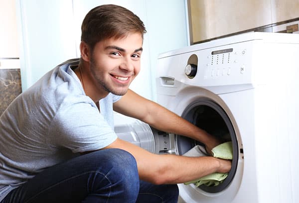 A man takes out laundry from a washing machine
