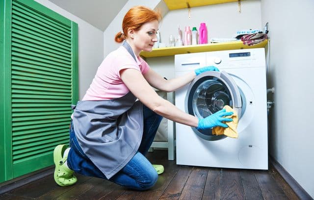 Lány tisztítja a mosógépet