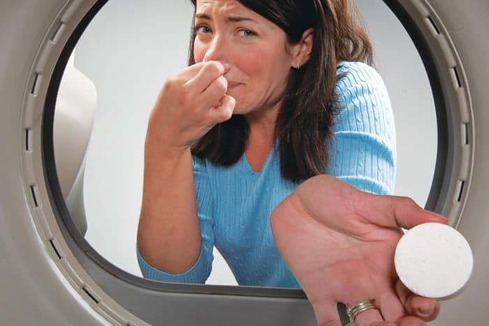 Woman adds a pill to the drum of a washing machine