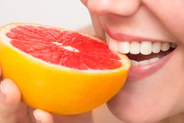 Žena jesť grapefruit
