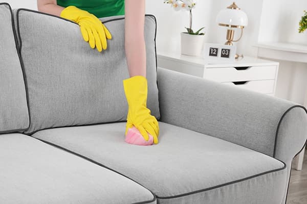 Nő tisztítja a kanapét