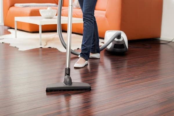 Woman vacuuming laminate flooring in living room