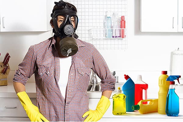 Mulher com máscara de gás ao lado de produtos químicos domésticos