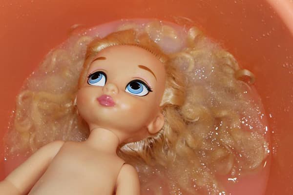 Lavar o cabelo de uma boneca em um amaciante
