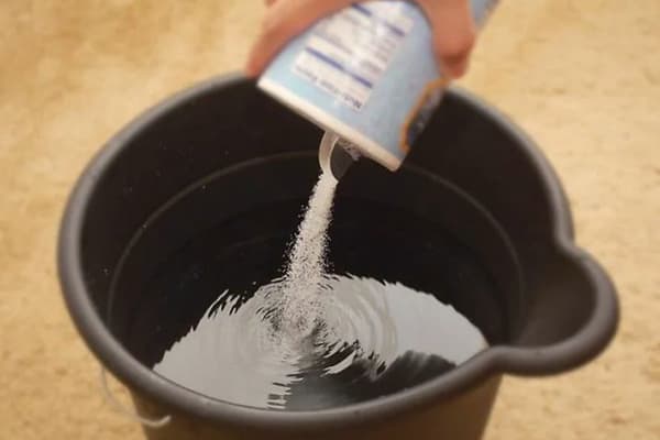 Přidání soli do kbelíku s vodou