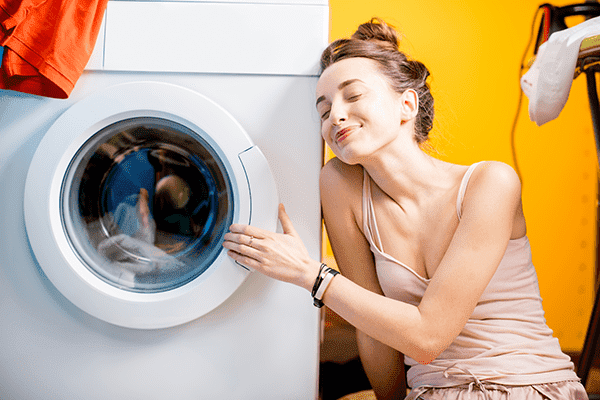 Das Mädchen ist glücklich mit der Waschmaschine