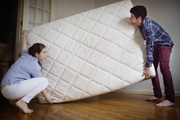 Couple carries a new mattress