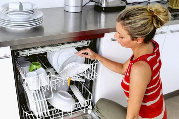 Garota tira pratos da máquina de lavar louça