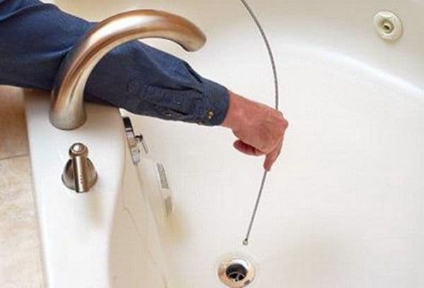 cleaning the bathroom drain with a cable