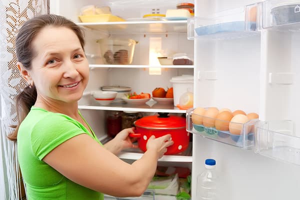 Nő serpenyőt tesz a hűtőszekrénybe