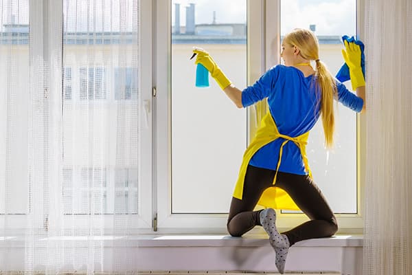 หญิงสาวบน windowsill ล้างหน้าต่าง