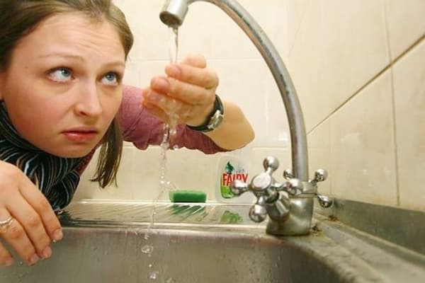 Femeia examinează apa de la robinet