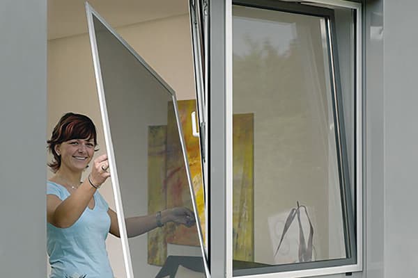 Kobieta usuwa siatkę z okna