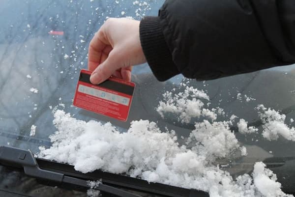 Почистване на колата от сняг с пластмасова карта