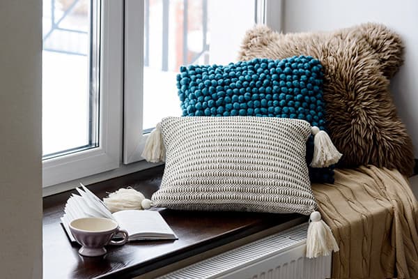 Pillows, cup and book on the windowsill