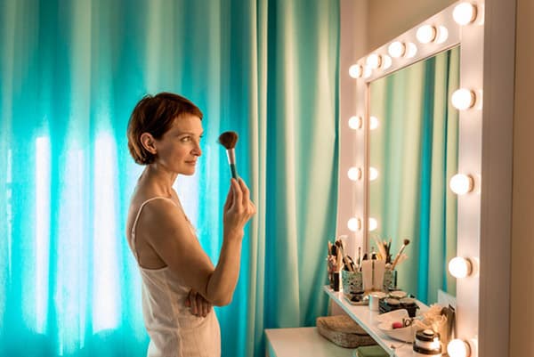 Femme se maquille devant un miroir