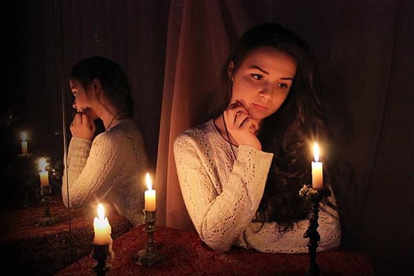 Fille assise au miroir avec des bougies
