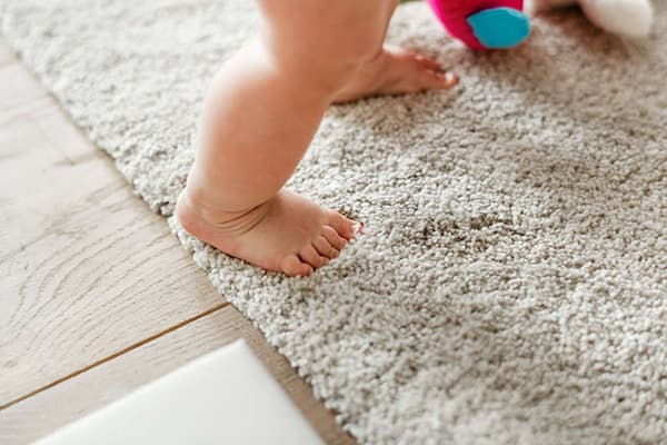 Vaikas vaikšto ant kilimo