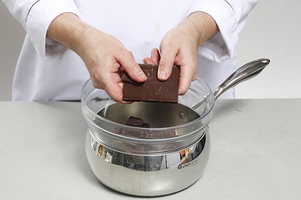 Cukiernik topi czekoladę w kąpieli wodnej