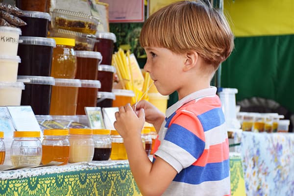 Un garçon goûte le miel à la foire